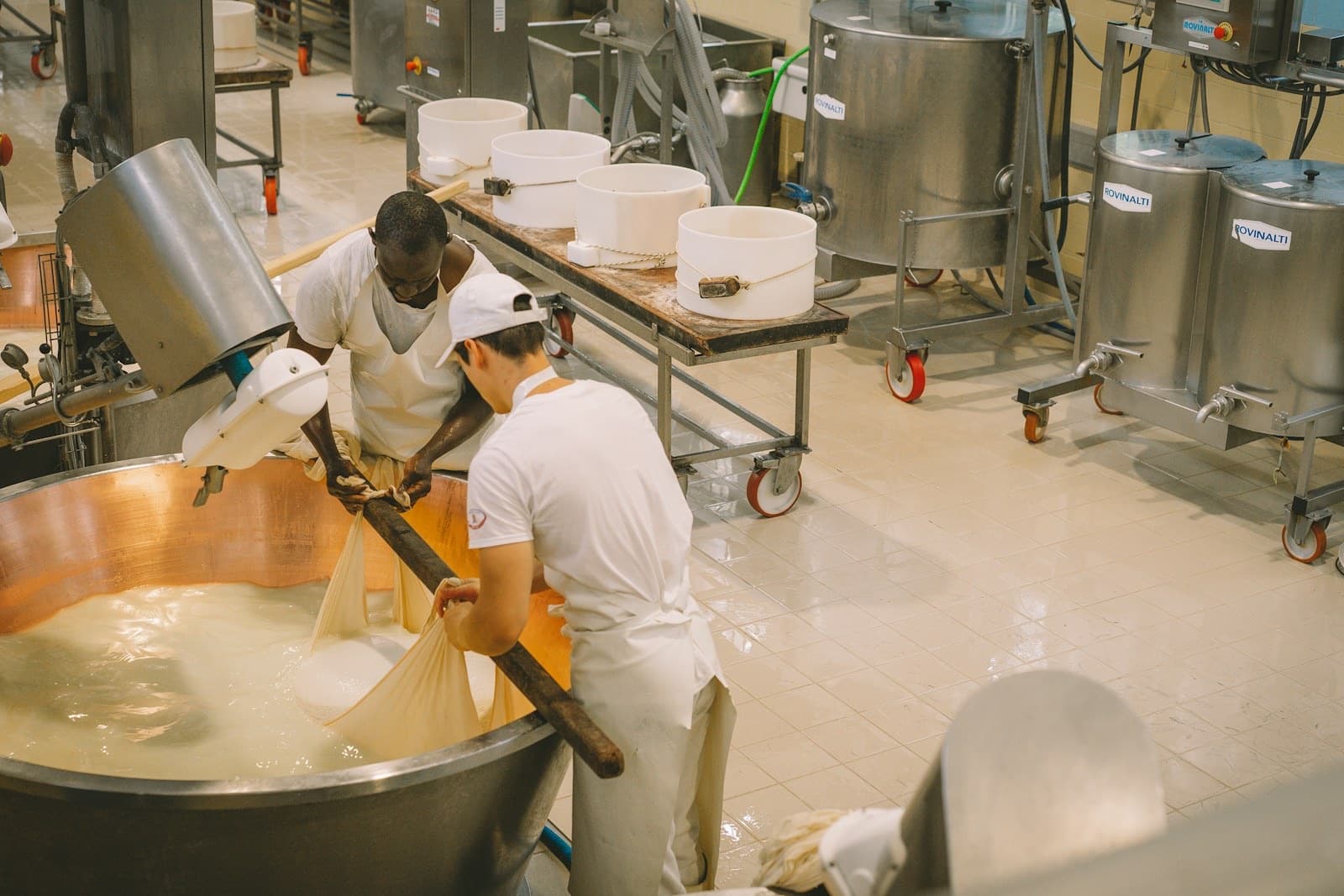 Queseros trabajando junto a las tinas de una quesería